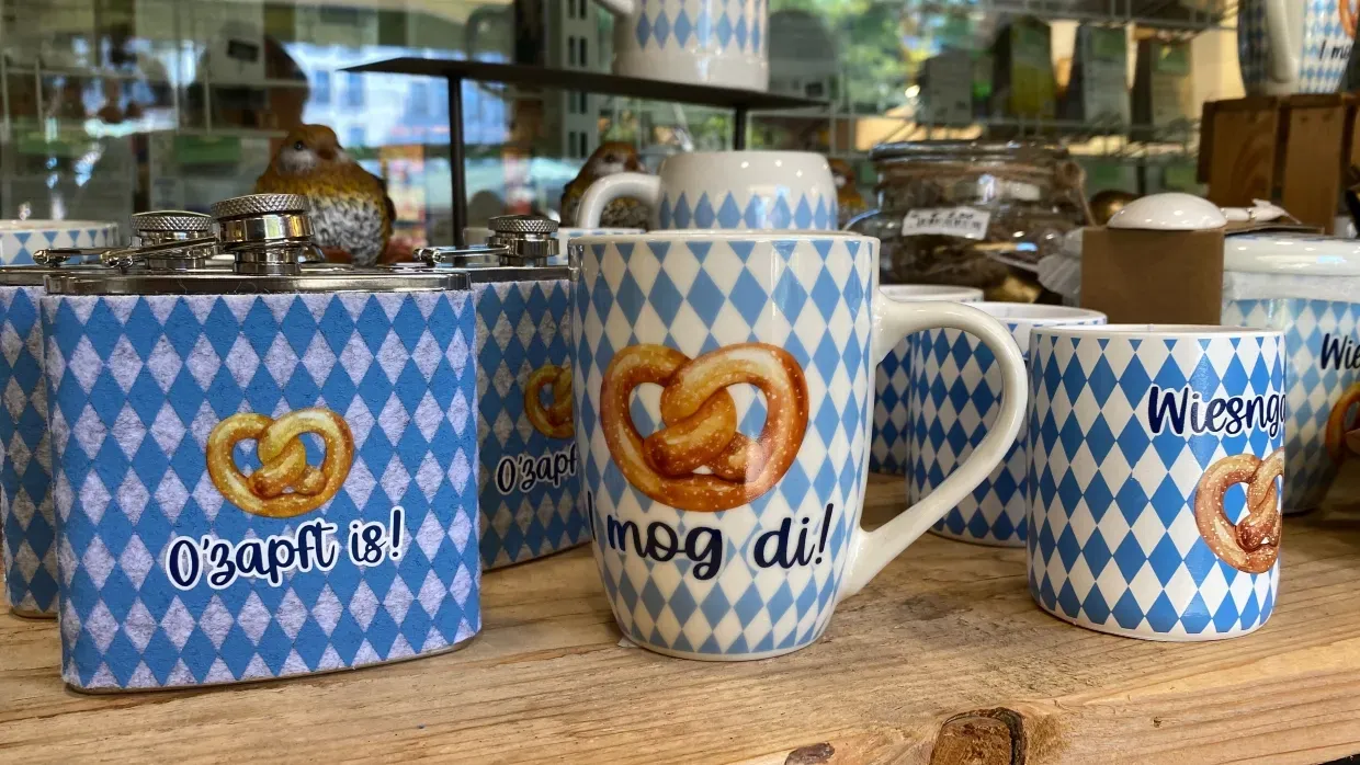 Oktoberfest-Souvenirs: Blau-weiße Tassen, Bierkrüge und Kerzen mit Brezenmotiv als Geschenkideen aus München