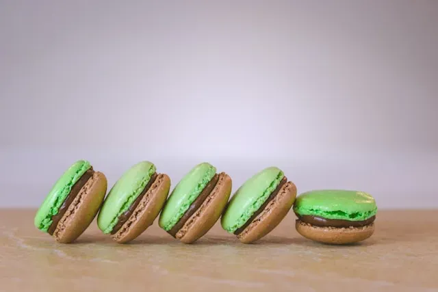 Grün-braune Macarons auf heller Holzfläche