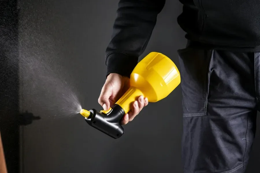 Hand hält gelben Handsprüher, der feinen Sprühnebel abgibt